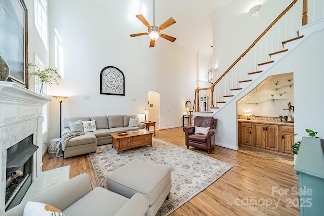 living area featuring stairs, light wood finished floors, arched walkways, and a high end fireplace