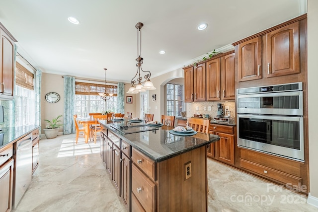 kitchen with arched walkways, stainless steel appliances, a kitchen island, tasteful backsplash, and dark stone countertops