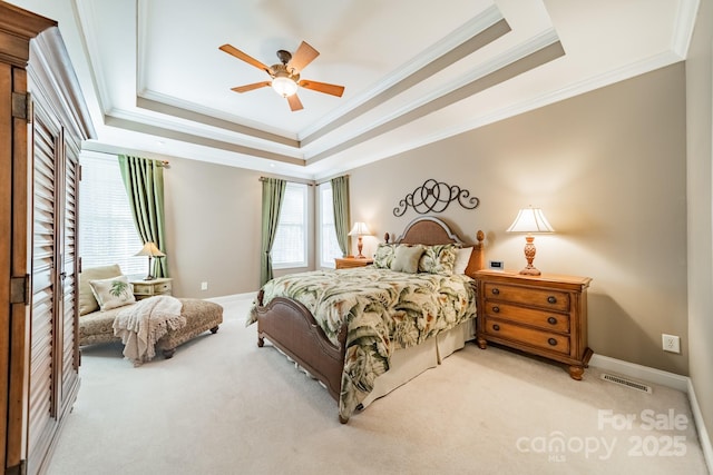 carpeted bedroom with a tray ceiling, visible vents, crown molding, and baseboards