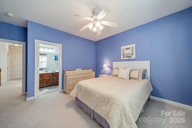 bedroom featuring a ceiling fan, light colored carpet, baseboards, and ensuite bathroom