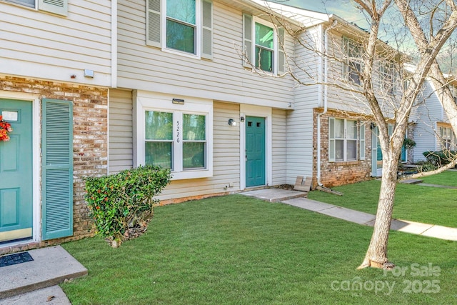 doorway to property with brick siding and a lawn