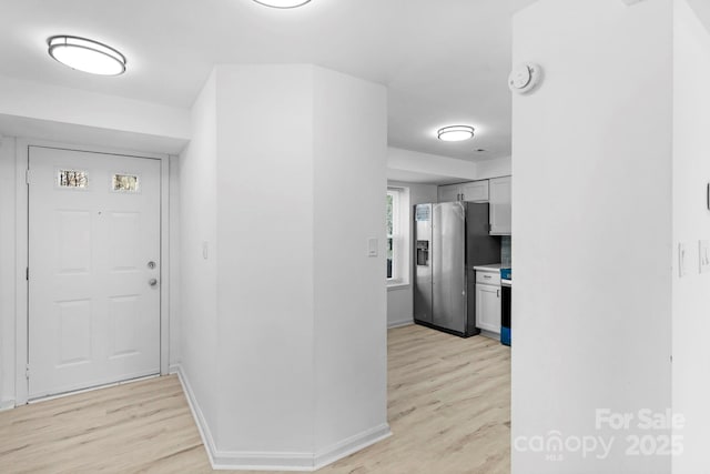 foyer entrance featuring light wood-style flooring and baseboards