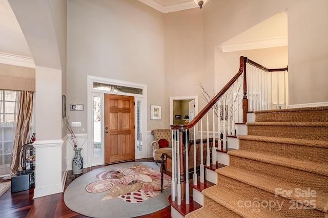 entrance foyer featuring hardwood / wood-style floors, crown molding, and a towering ceiling