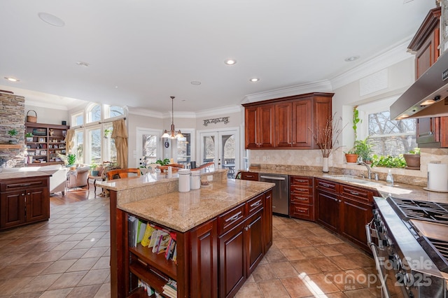 kitchen with hanging light fixtures, appliances with stainless steel finishes, a kitchen island, and a wealth of natural light