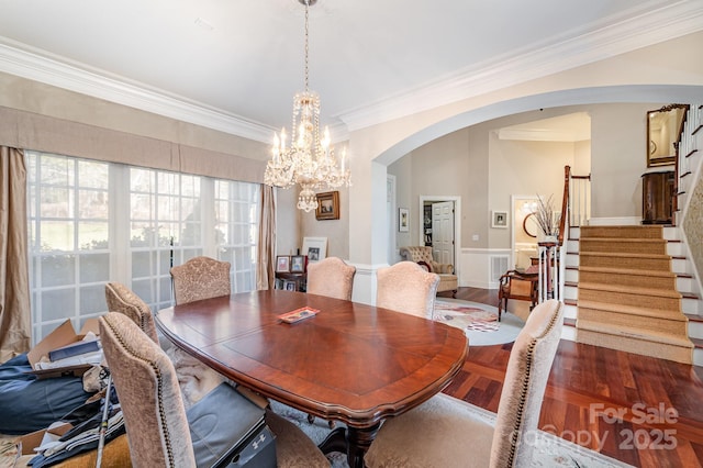 dining area featuring dark wood-type flooring, crown molding, and a notable chandelier