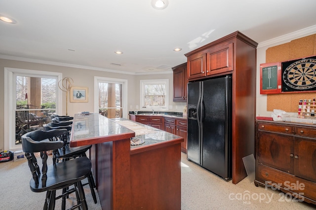 kitchen with french doors, ornamental molding, black fridge with ice dispenser, and a kitchen bar