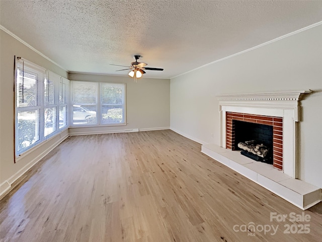 unfurnished living room with a tiled fireplace, crown molding, a textured ceiling, and light wood-type flooring