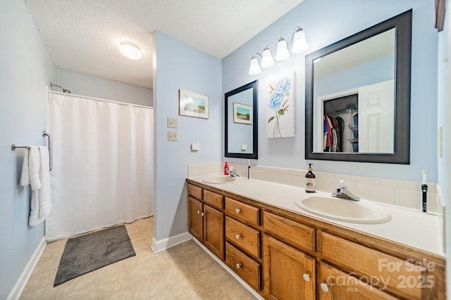 full bath with a textured ceiling, double vanity, and a sink