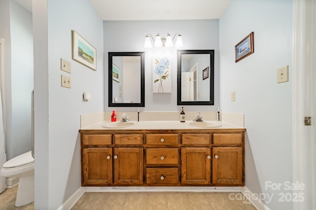 bathroom featuring baseboards, a sink, toilet, and double vanity