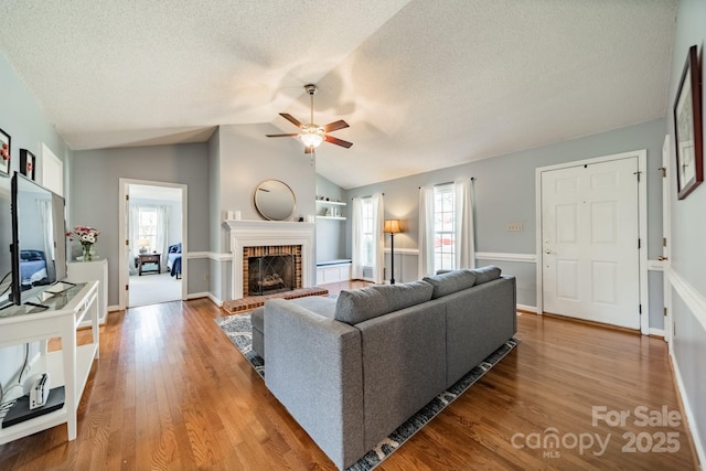 living room with lofted ceiling, a textured ceiling, a fireplace, and wood finished floors