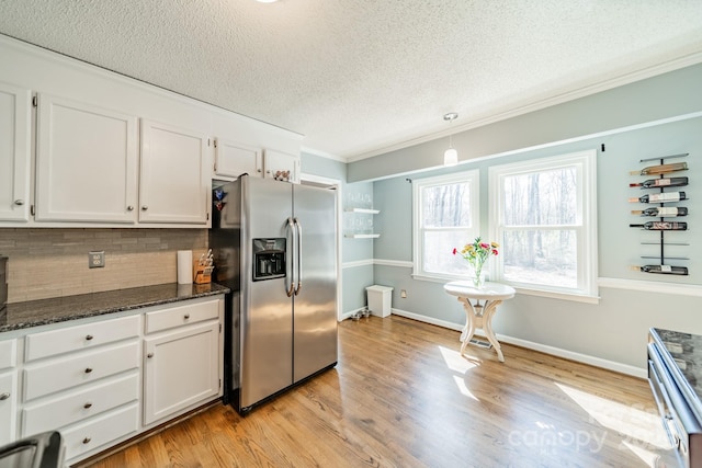 kitchen featuring backsplash, light wood-style floors, white cabinetry, dark stone counters, and stainless steel fridge