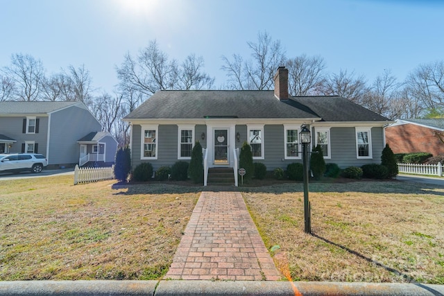 ranch-style home featuring a chimney, fence, a front lawn, and roof with shingles