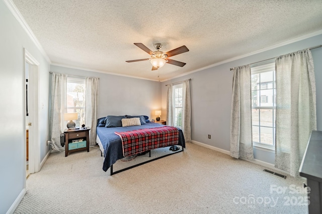 carpeted bedroom with visible vents, ornamental molding, a ceiling fan, a textured ceiling, and baseboards