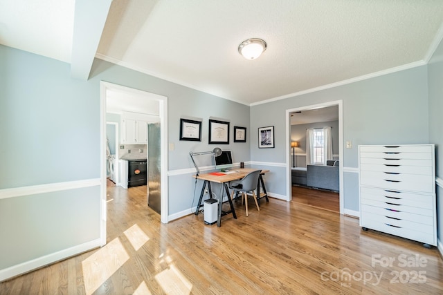 dining area with ornamental molding, light wood finished floors, a textured ceiling, and baseboards