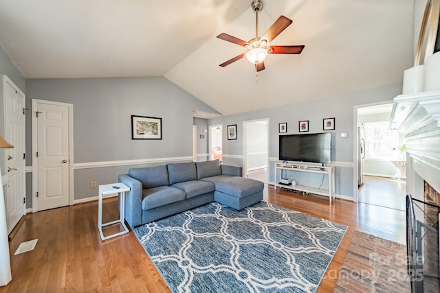 living room with visible vents, a ceiling fan, wood finished floors, vaulted ceiling, and a fireplace