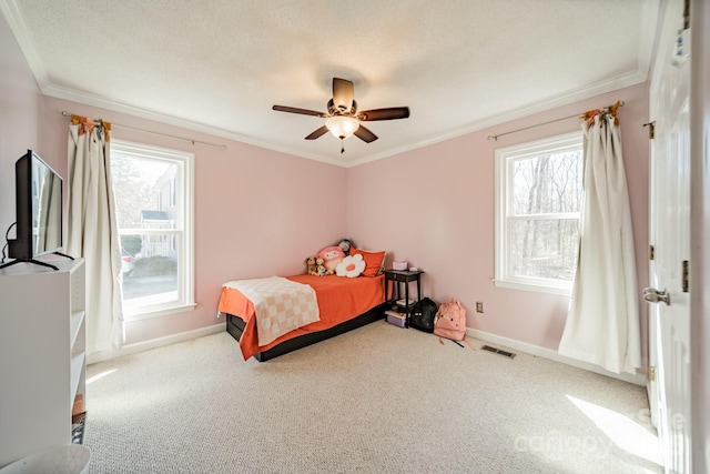 carpeted bedroom featuring visible vents, baseboards, a ceiling fan, ornamental molding, and a textured ceiling