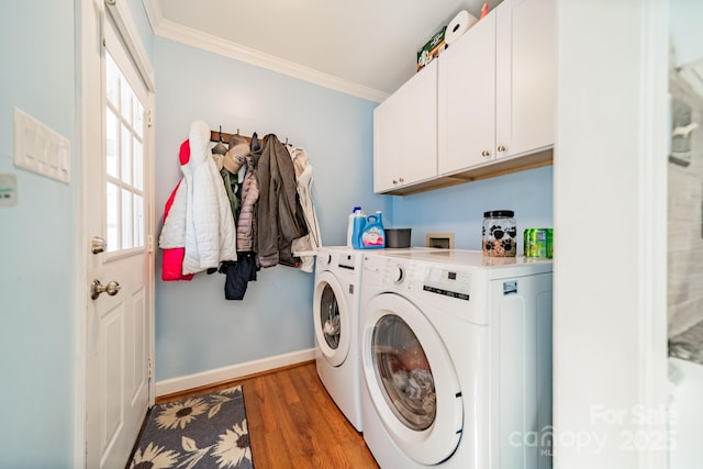 clothes washing area with baseboards, light wood-style floors, cabinet space, washing machine and clothes dryer, and crown molding