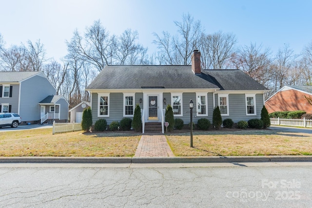 view of front of property featuring a front yard, roof with shingles, fence, and a chimney