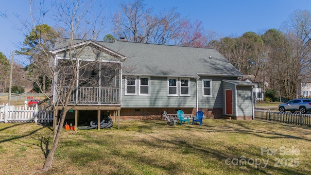 rear view of property with a sunroom, roof with shingles, a yard, and fence