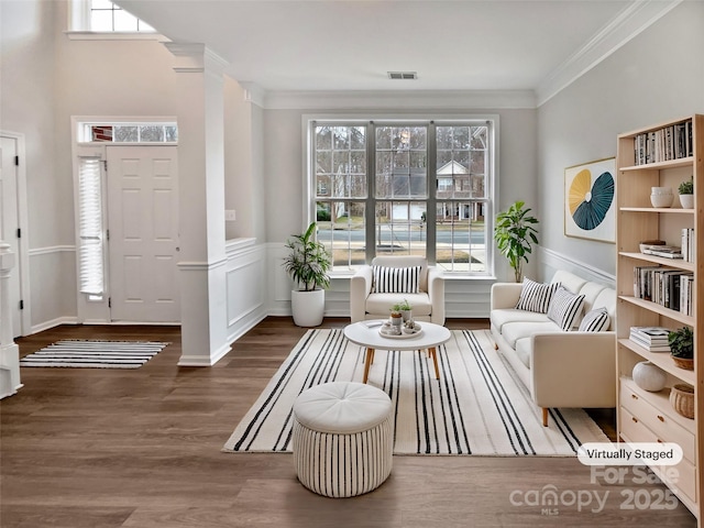 living area with dark wood-style floors, ornamental molding, a wainscoted wall, and visible vents