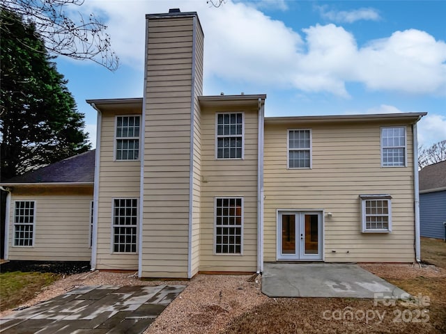 back of property with french doors, a chimney, and a patio area