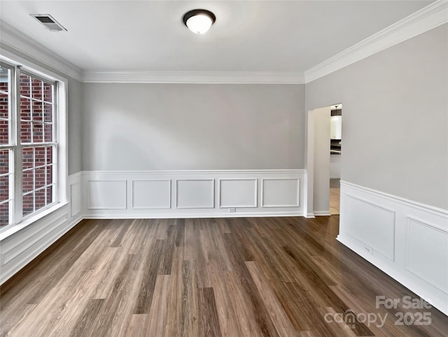 unfurnished room with ornamental molding, dark wood-type flooring, wainscoting, and visible vents