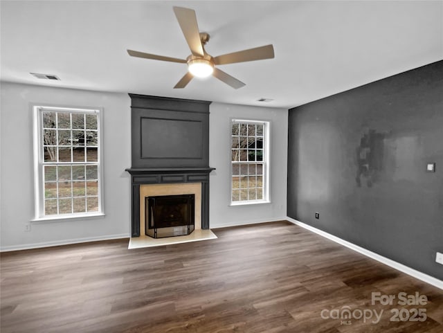 unfurnished living room featuring dark wood-style floors, baseboards, a fireplace, and visible vents