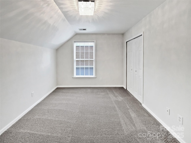 additional living space with baseboards, visible vents, vaulted ceiling, and carpet flooring