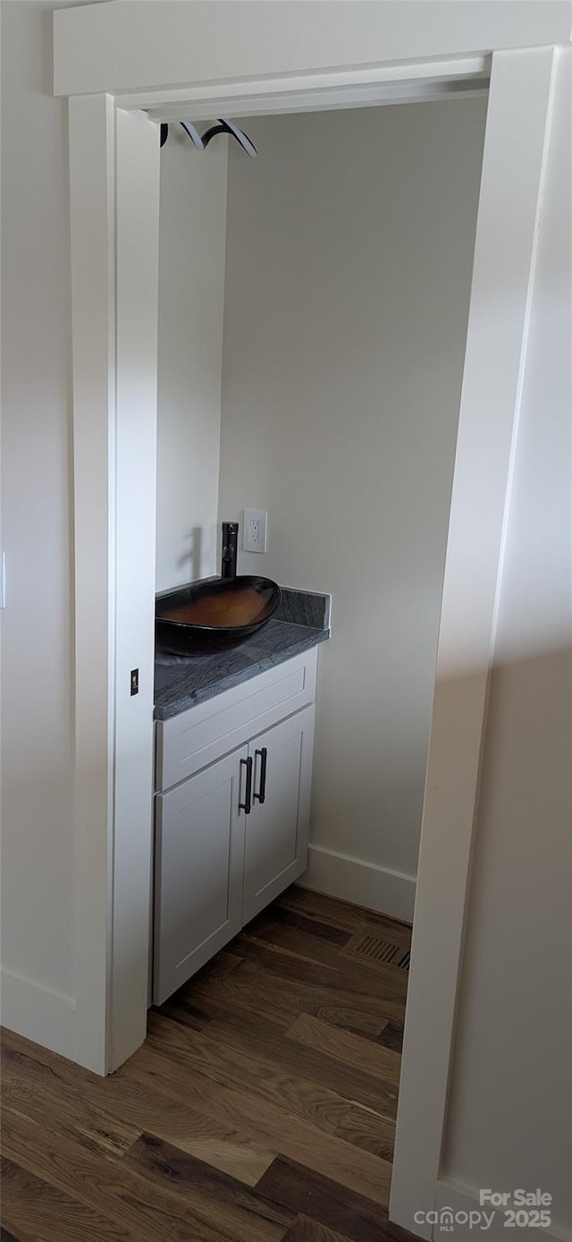 bathroom with baseboards, wood finished floors, and vanity