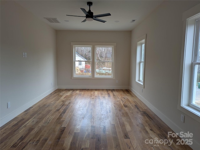 empty room featuring visible vents, a ceiling fan, baseboards, and wood finished floors