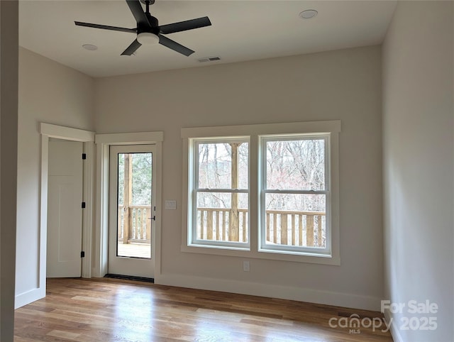 interior space with visible vents, a ceiling fan, baseboards, and wood finished floors