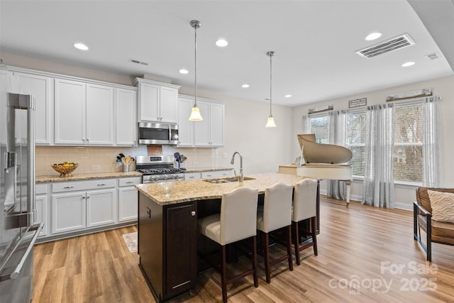 kitchen featuring appliances with stainless steel finishes, a sink, visible vents, and light wood-style floors