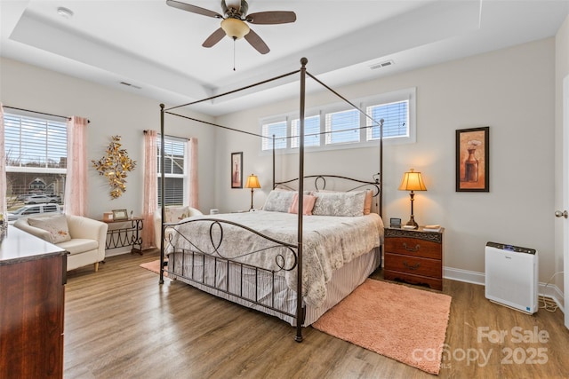 bedroom with visible vents, multiple windows, and wood finished floors