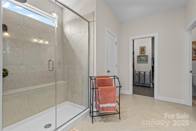 bathroom featuring a shower stall, baseboards, and tile patterned flooring