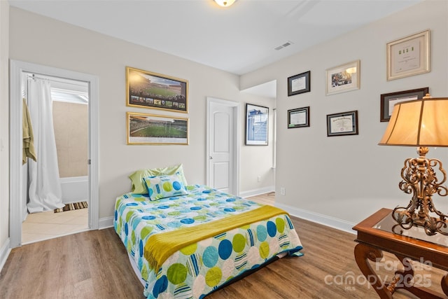 bedroom with visible vents, baseboards, and wood finished floors