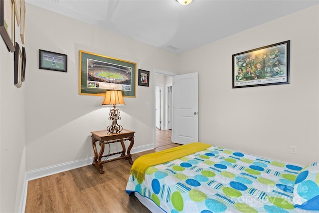 bedroom featuring visible vents, baseboards, and wood finished floors