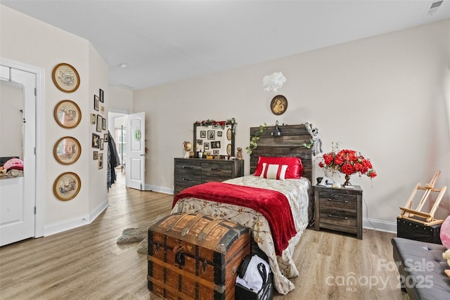 bedroom with baseboards, visible vents, and wood finished floors