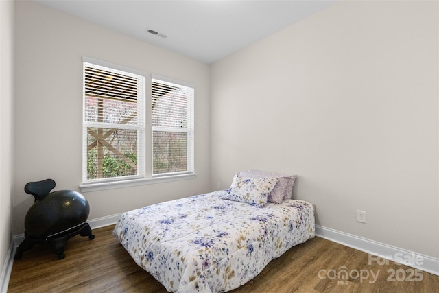 bedroom with wood finished floors, visible vents, and baseboards