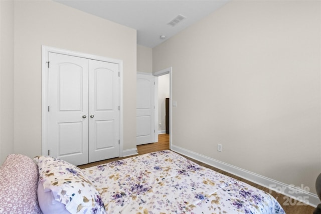 bedroom featuring a closet, visible vents, baseboards, and wood finished floors