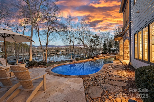 outdoor pool with a patio and a water view