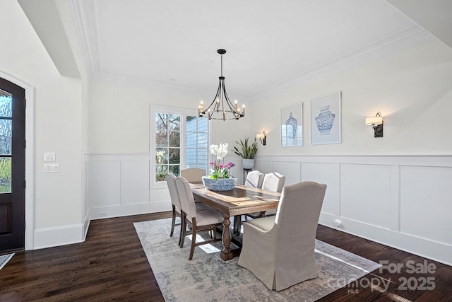 dining room with a chandelier, wainscoting, dark wood finished floors, and crown molding