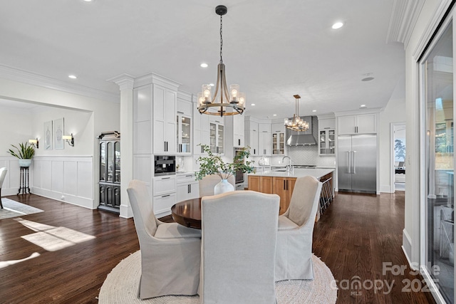 dining area featuring crown molding, a wainscoted wall, dark wood finished floors, and a notable chandelier