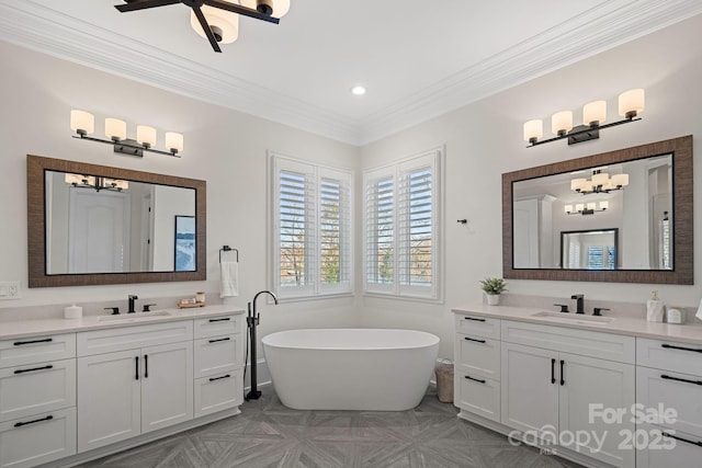 full bathroom with a freestanding bath, two vanities, a sink, and crown molding