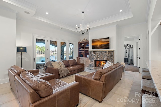 living room featuring a tray ceiling, crown molding, a stone fireplace, and an inviting chandelier