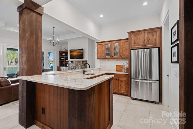 kitchen with a peninsula, a sink, open floor plan, freestanding refrigerator, and glass insert cabinets