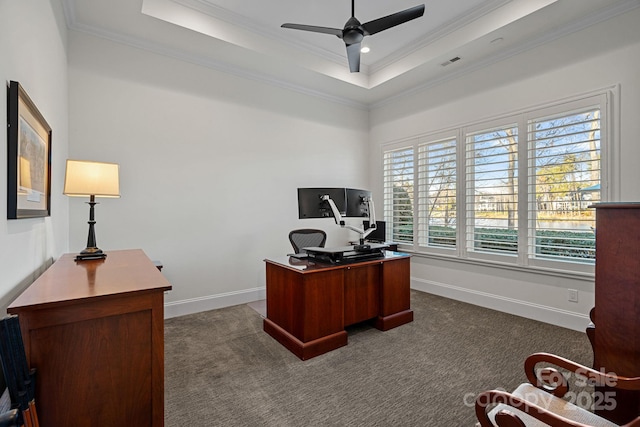 office area featuring a tray ceiling, visible vents, dark carpet, ornamental molding, and ceiling fan