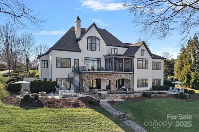 rear view of house featuring stone siding, stairs, a lawn, and a patio