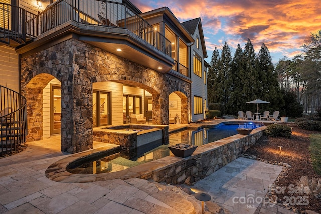 back of house with a patio, a balcony, an in ground hot tub, an outdoor pool, and stairs