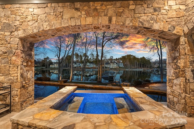 view of pool featuring arched walkways and a water view