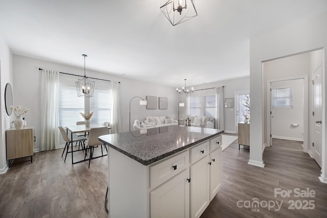 kitchen featuring dark wood-type flooring, white cabinetry, dark stone countertops, a notable chandelier, and a kitchen island